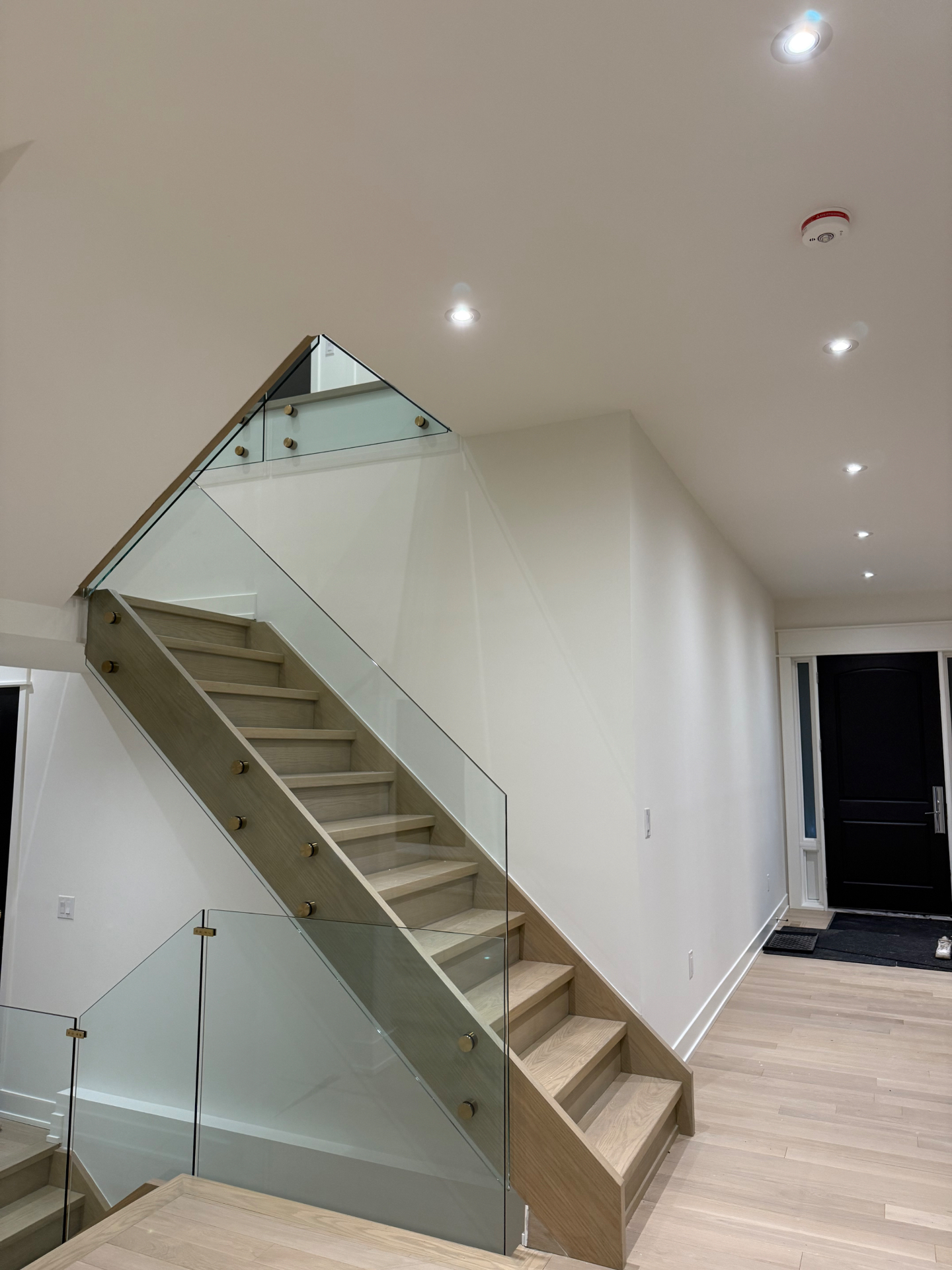 Modern staircase with frameless glass railing and brass hardware